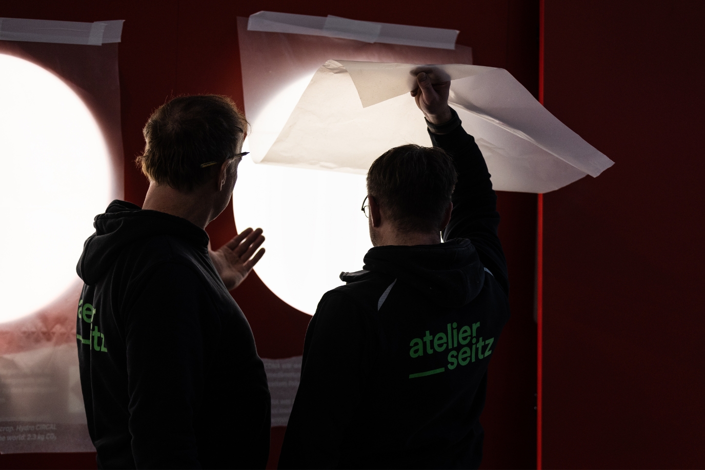 Zwei Atelier Seitz Mitarbeiter stehen vor eine Folie und besprechen sich